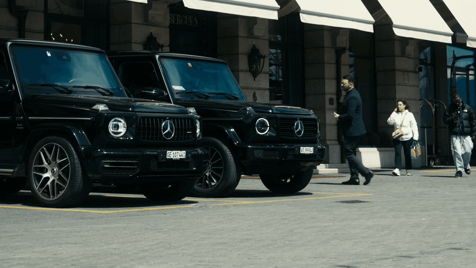Two black SUVs parked outside a hotel entrance