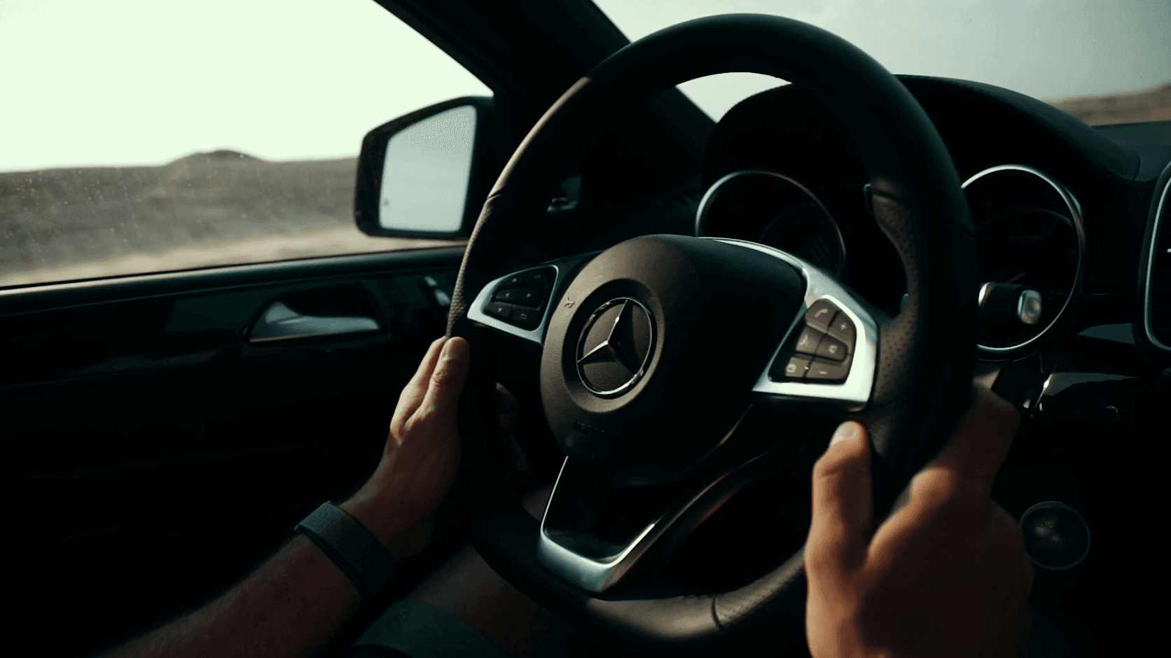 Chauffeur's hands on the steering wheel of a luxury car