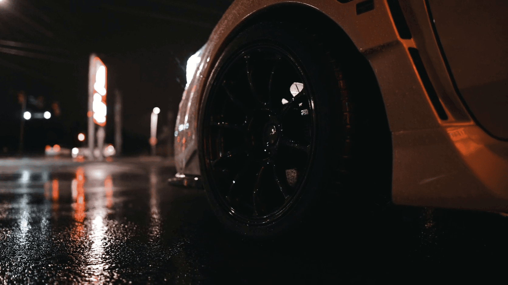 Close-up of a car wheel on a wet street at night